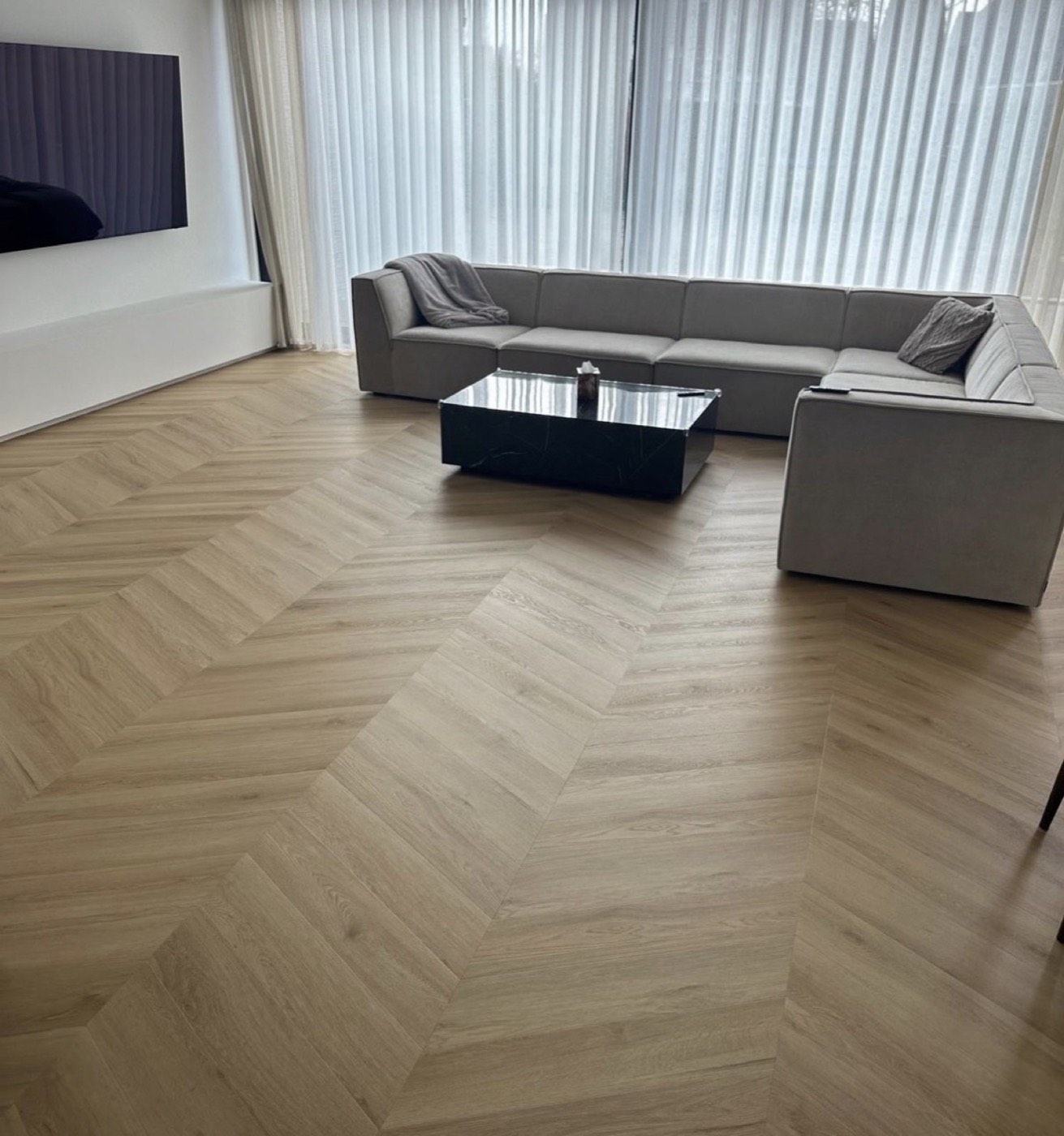 Wohnzimmer mit fertig verlegtem Chevron-Boden in Eiche