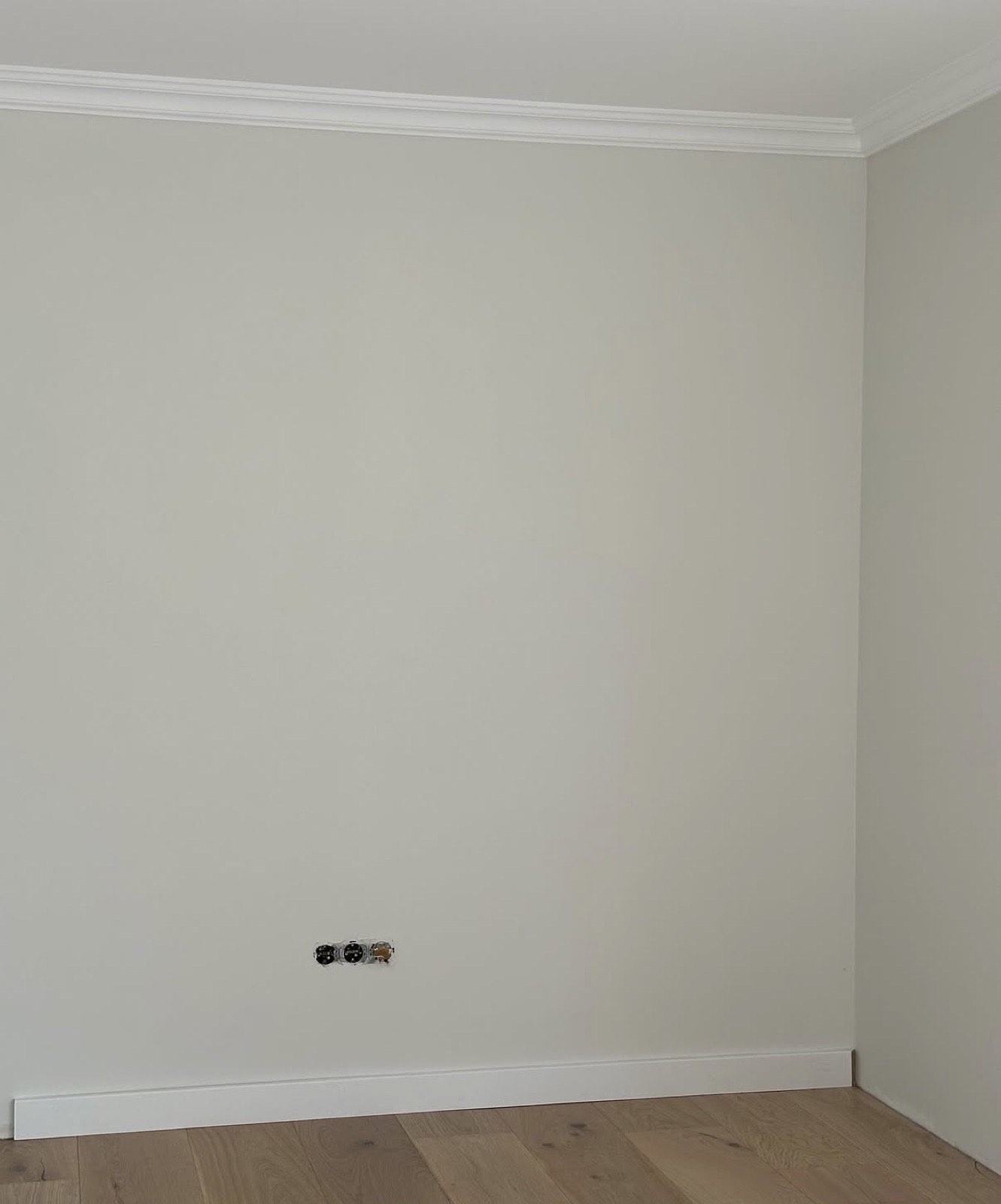 Fertige Wand mit Stuckleiste, weißer Sockelleiste und Parkett