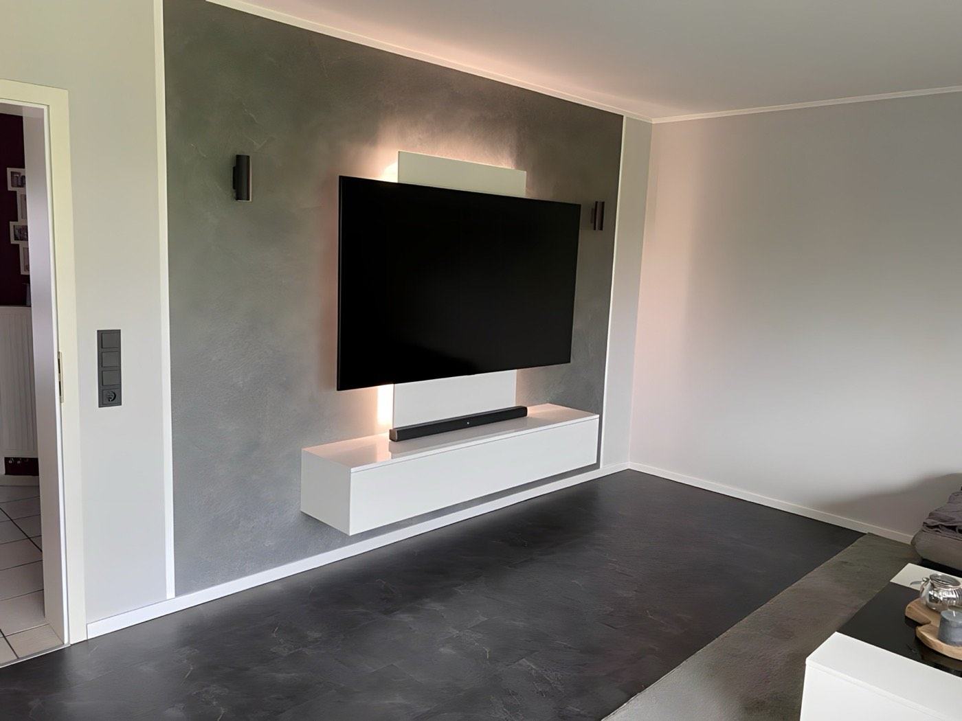 Wohnzimmer mit Spachteltechnik-Wand und dunklem Designboden – ausgeführt von PR Raumdesign